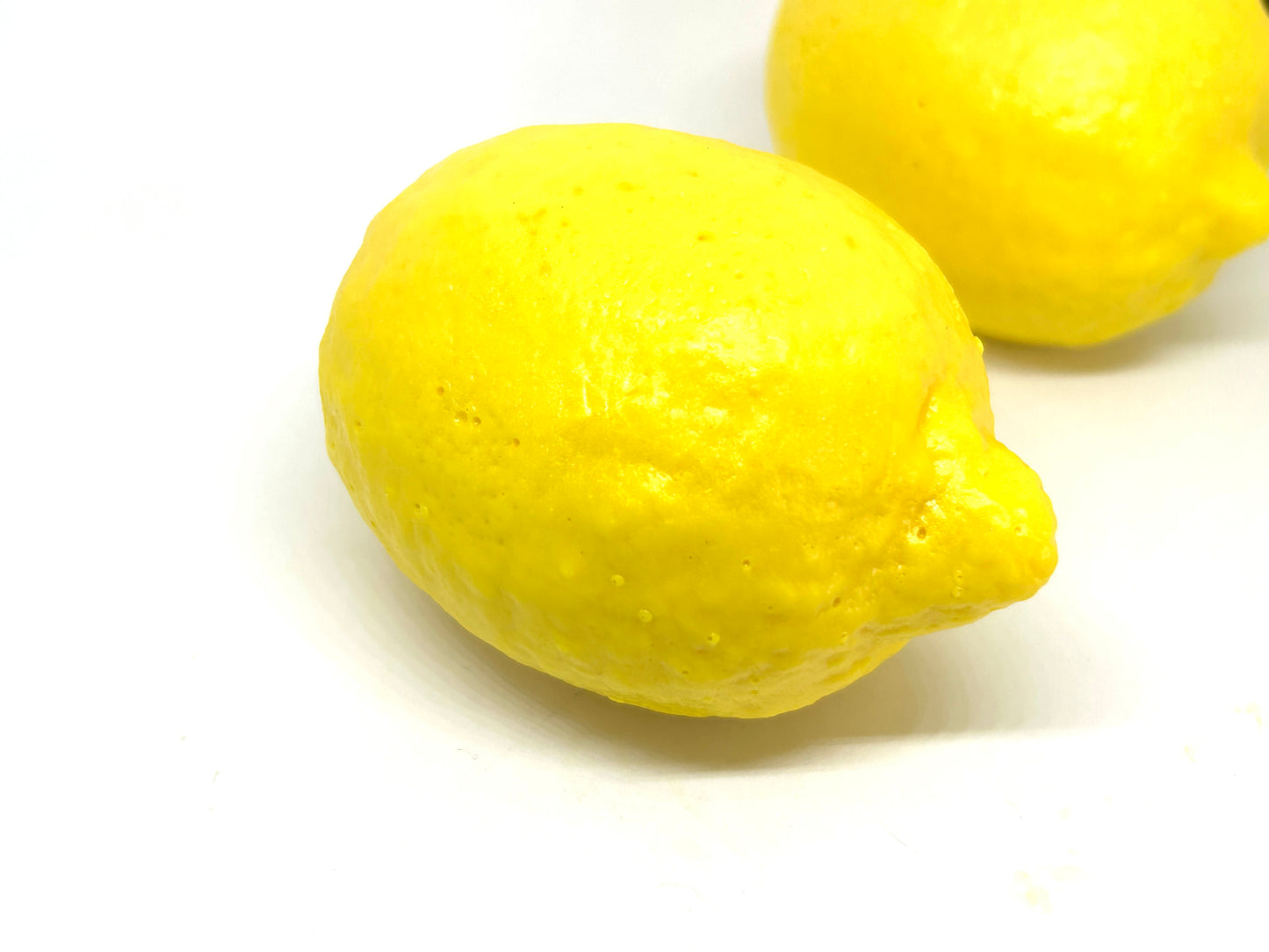 Two lemon shape soaps on a white background